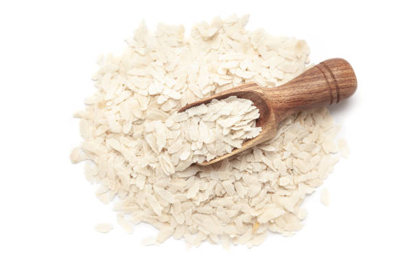 A pile of Organic Flattened rice (Oryza Sativa) or Poha with a wooden scoop, isolated on a white background. Top view